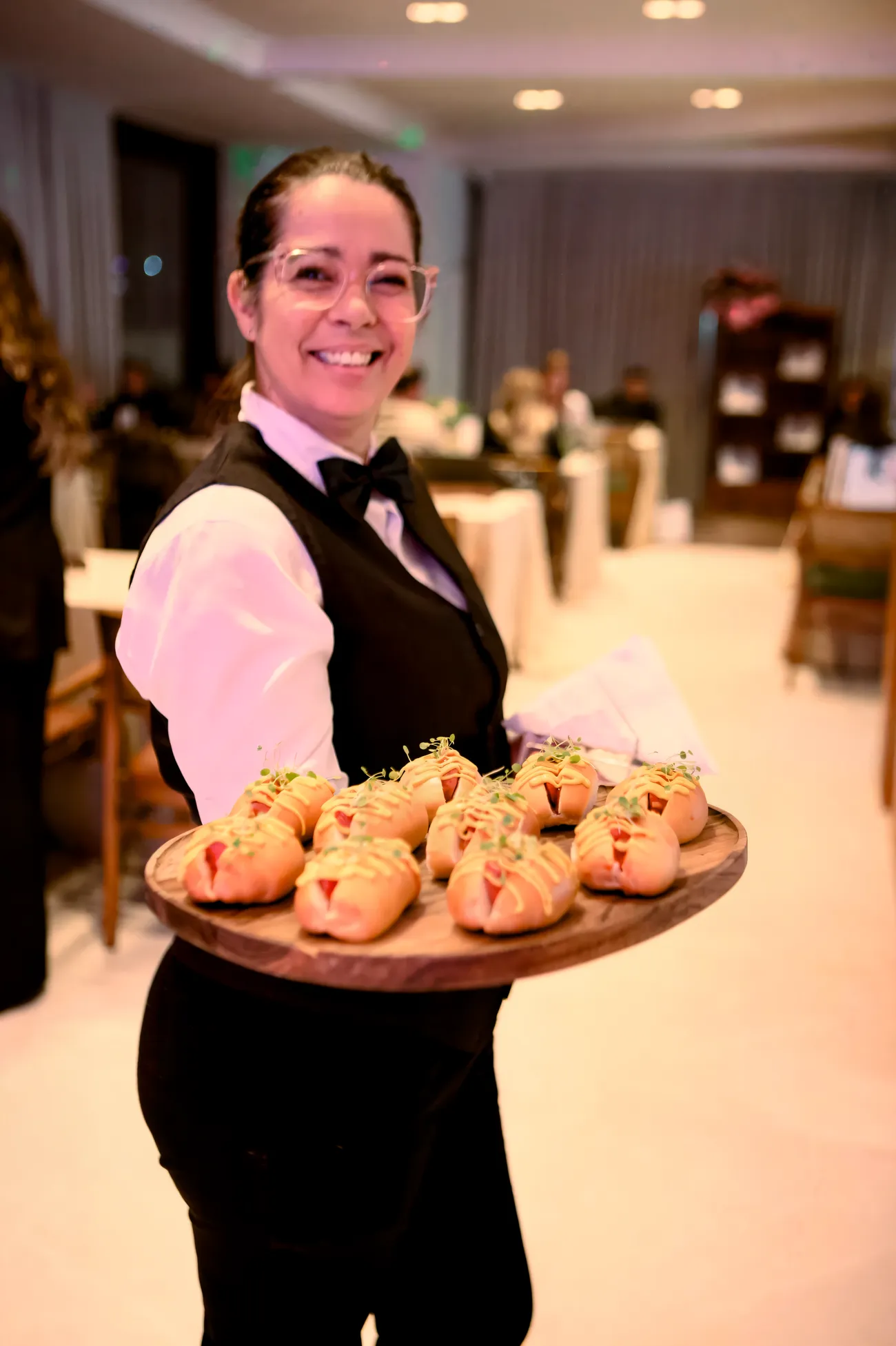 Garçonete com bandeja de mini hot dogs